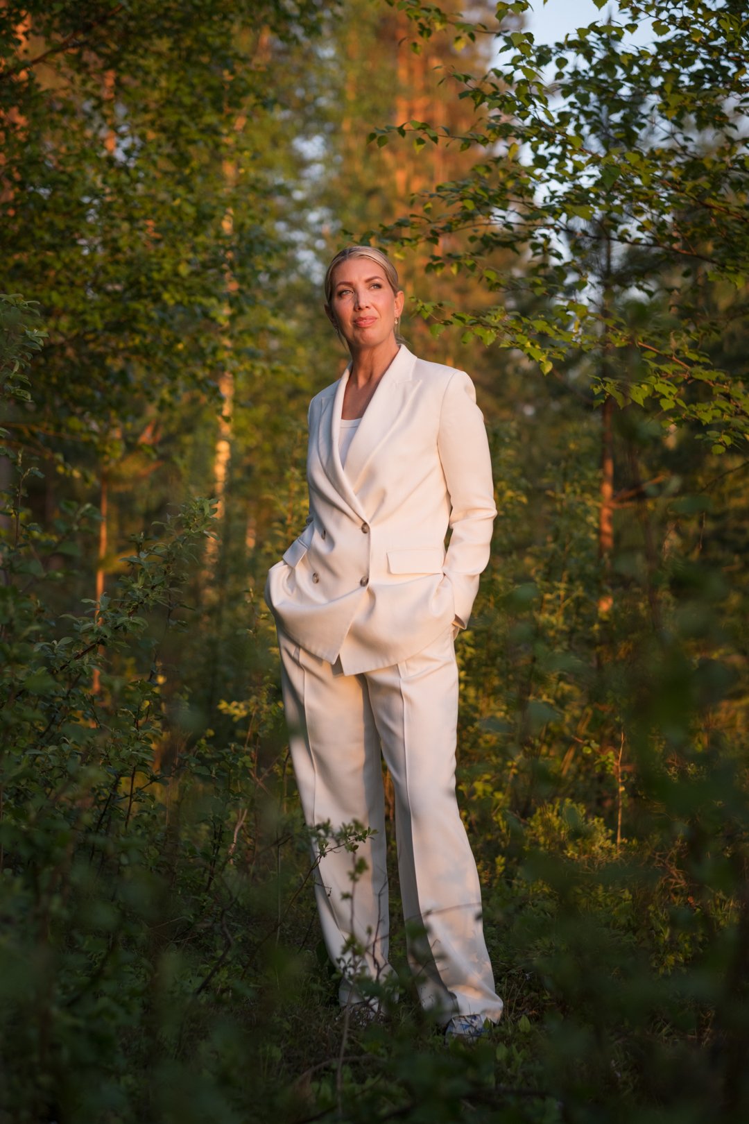 Lina Skandevall standing among trees in warm evening light