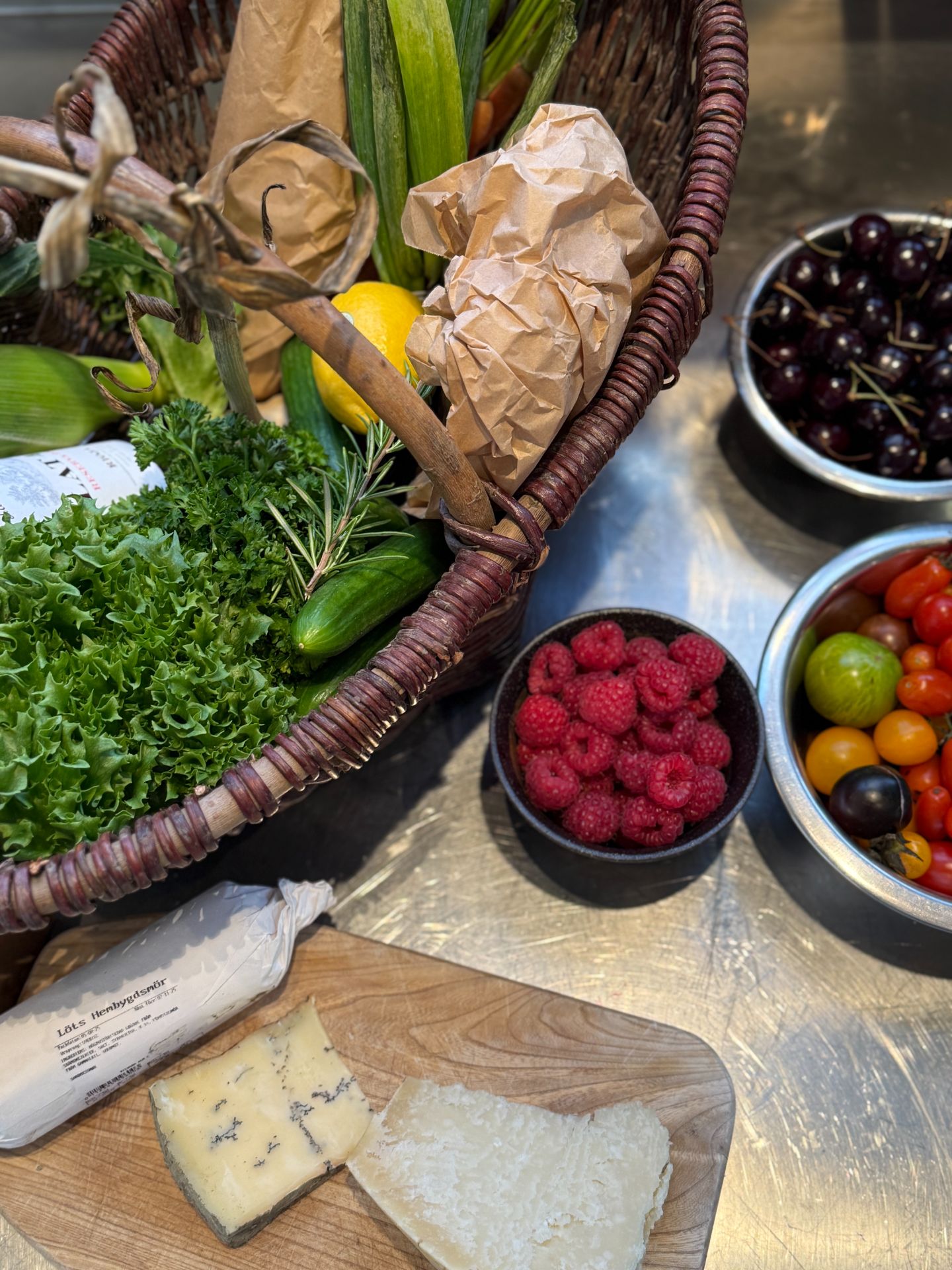 A basket of vegetables with tomatoes, berries, cheese and butter.