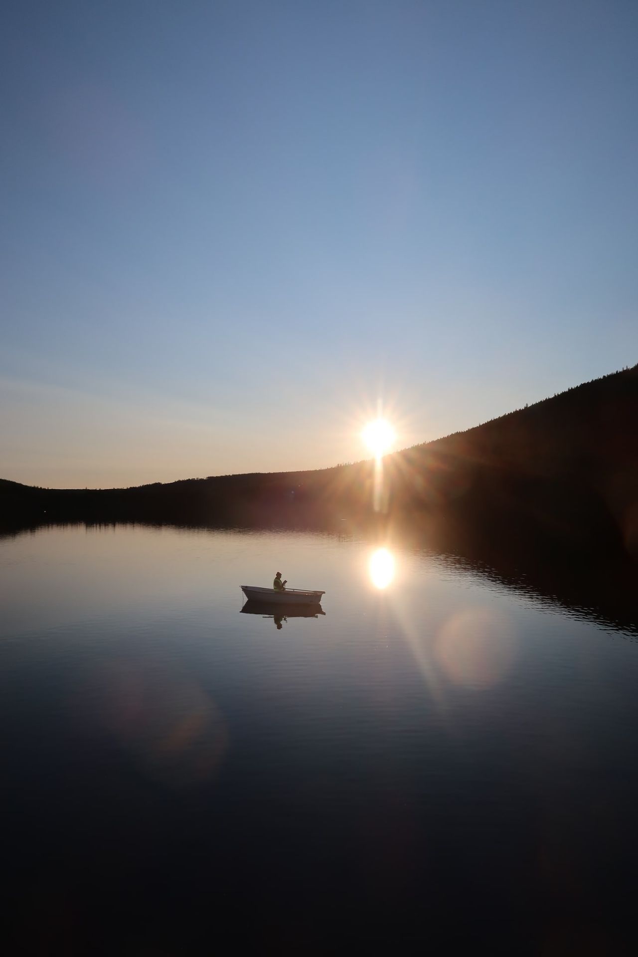 A rowing boat on the lake beneath a sky lit by the setting sun.