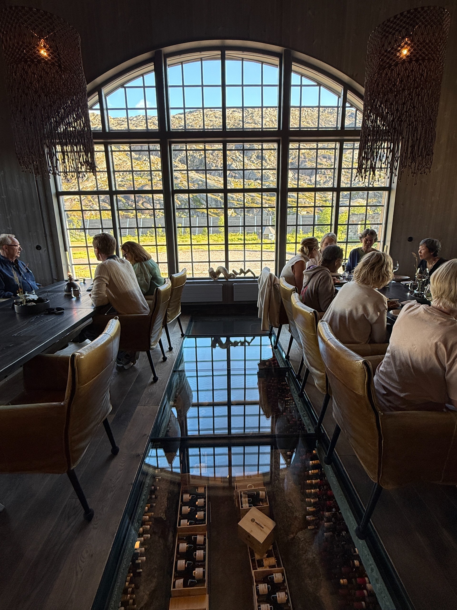 Diners sit beside an arched window and a glass floor revealing the wine cellar below.