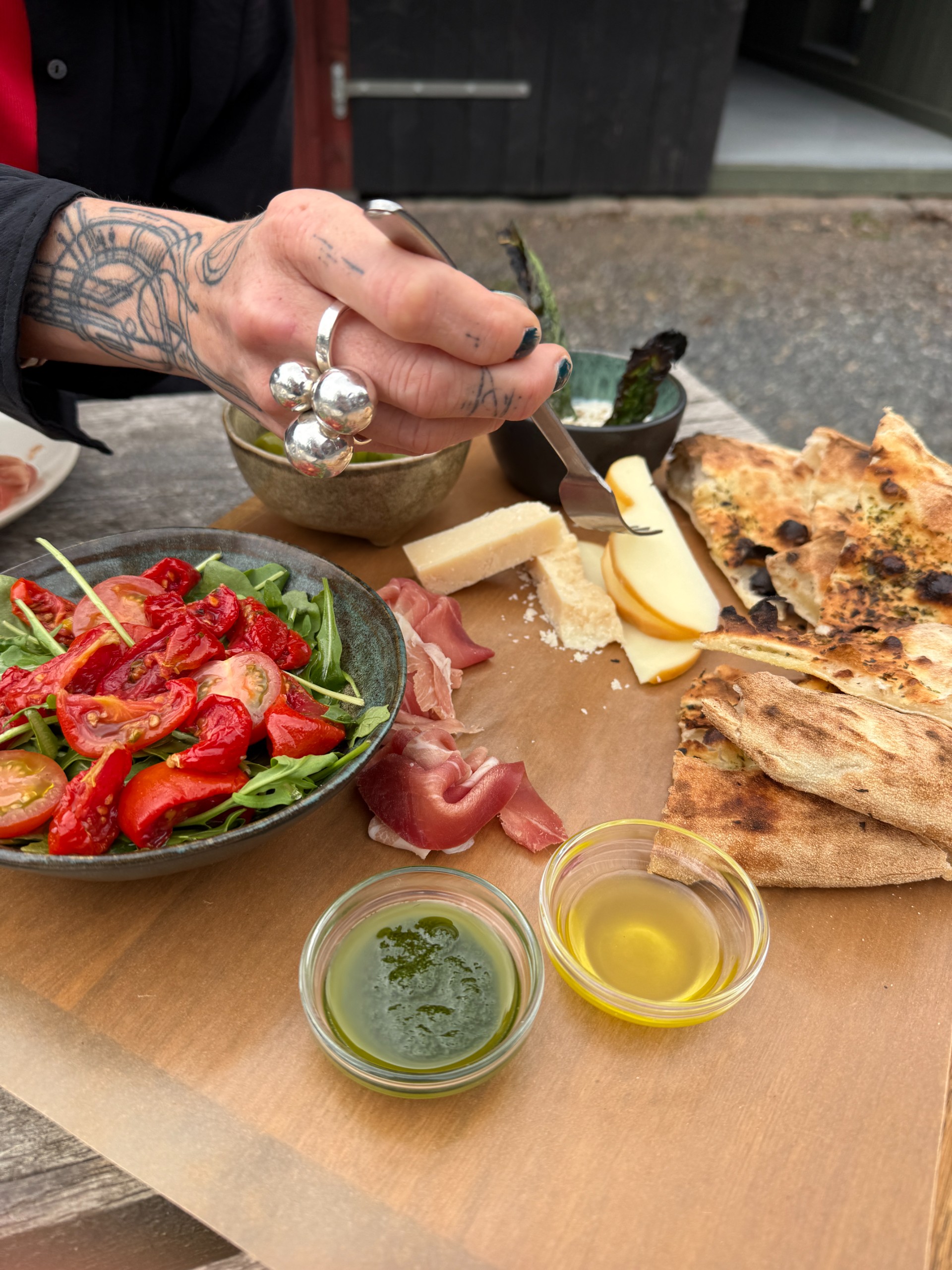 Antipasti with cured meat, cheese, tomatoes, rocket and charred bread on a sharing board.